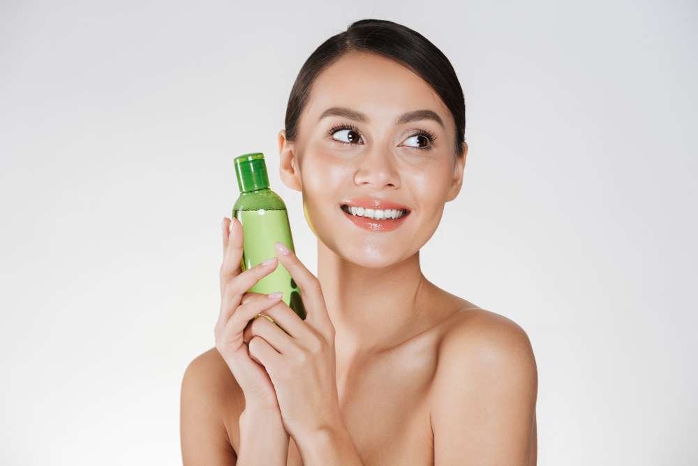 Woman with clear skin holding hyaluronic acid serum (anti-inflammatory) for acne relief.